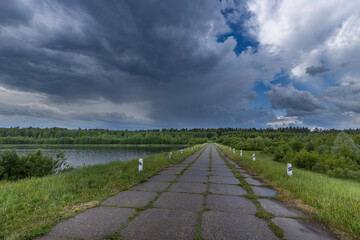 A road with a few poles and a lake in the background
