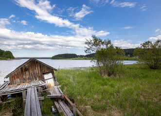 A small wooden cabin sits on a dock by a lake