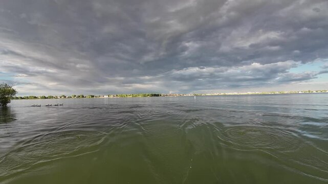Lake view and wake behind a stern of recreational rowing shell, rower POV perspective, summer on Boyd Lake in Colorado