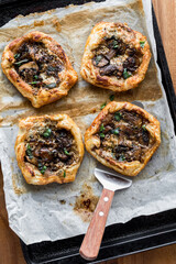 Gourmet savoury mushroom pastries on a parchment lined baking sheet.