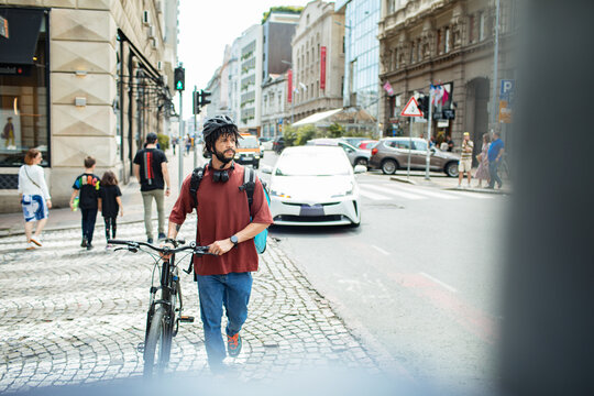 Delivery man with large backpack riding bicycle in urban setting