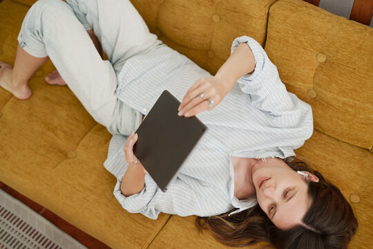 Woman Laying on Couch Using Tablet