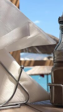  A woman pulls napkins from a napkin holder. Taking napkin on table near sea