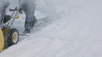 A man removes snow with a snowplow. Difficult weather conditions.