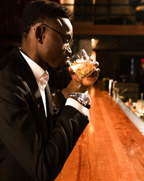 A successful man in expensive and luxurious clothes drinking alcohol 