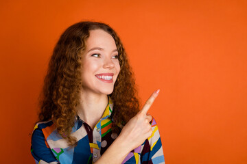 Photo of lovely pretty adorable girl wear trendy print clothes look empty space isolated on vibrant orange color background