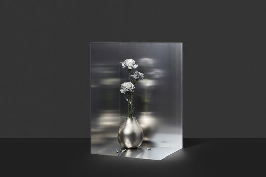 Composition of three flowers in shiny dark container 