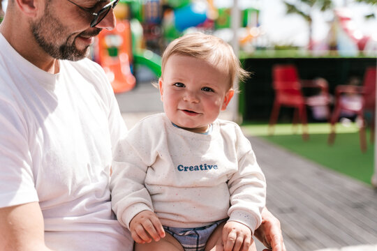 Crop cheerful man with cute smiling baby in park