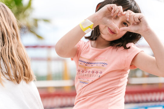 Happy little girl showing heart sign in park