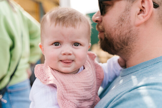 Crop man carrying happy infant on sunny day