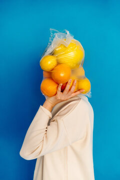 Person holding bag of citrus fruits overhead