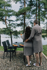 A man and woman standing next to a table with food on it.