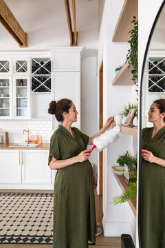 Pregnant Woman Dusting Shelves in Kitchen