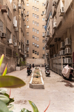 Narrow city street with motorcycles and air conditioning units