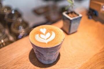 A close-up shot of a beautifully crafted latte with latte art in a ceramic cup on a wooden table