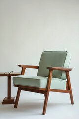 Mid-century wooden armchair with mint green fabric cushion and side table with eyeglasses