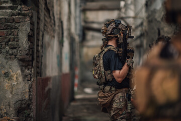Fototapeta premium Side view of soldiers on a mission in action at abandoned building.