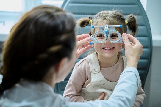 Smiling girl doing eye test with optometrist