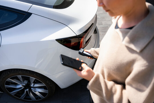 A woman connects a charger to an electric car