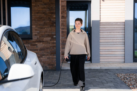 A woman connects a charger to an electric car