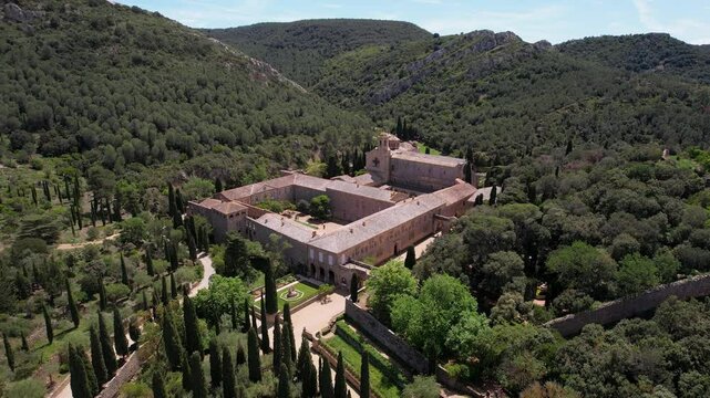 Forward reveal aerial shot of Fontfroide Abbey on sunny day. Narbonne, France.