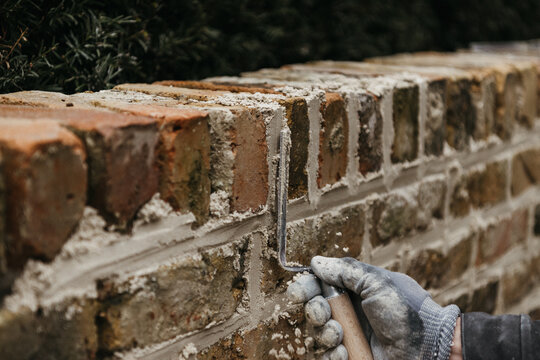 Gloved hand applying mortar to bricks