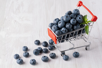 A shopping cart or supermarket trolley with blueberries on white background