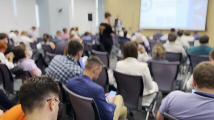 Business conference with many attendees sitting and listening to presentations in a modern conference room. Professionals engaged in discussion and networking.