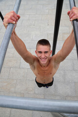 Young boy, teenager doing outdoor sport, workout on horizontal bar, healthy sport life