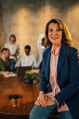Happy mature executive posing at office on meeting of interracial team