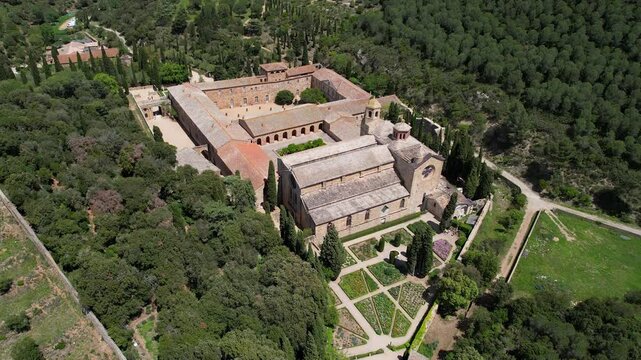 Backward reveal aerial footage of Fontfroide Abbey on sunny day. Narbonne, France.