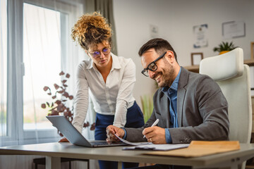 man sign document with help of a woman colleague at office