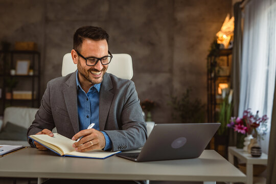 Adult man work from home write data from the laptop in a notebook