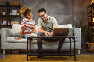 Man with earphones work from home write on clipboard with girlfriend