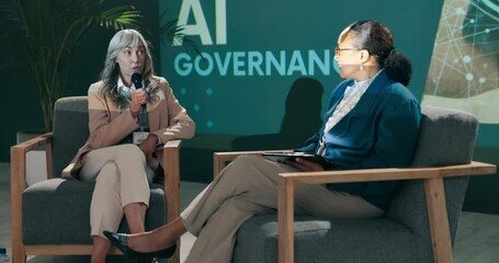 Conference, business women and speaker with question talk or speech at startup on stage with host. Guest, technology and event at seminar for presentation on ai governance, policy or risk management