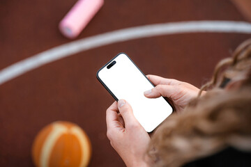 A woman uses a mobile phone with white screen on a sports field