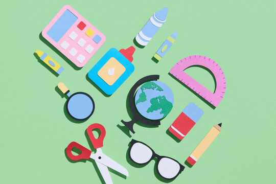 Colorful notebooks and office supplies on green background