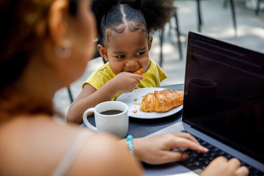 Female freelancer using laptop by daughter at cafe