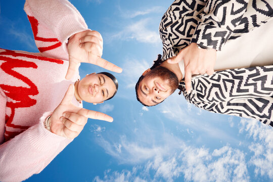 Friends making gestures against the blue sky