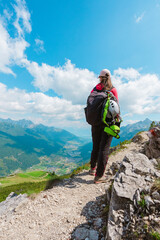 Woman Climber Standing on a Stony Alpine Hiking Trail Looking Down Into the Mountain Vally Landscape