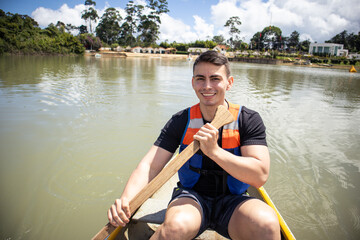 young man in life jacket rowing a small boat on a lake