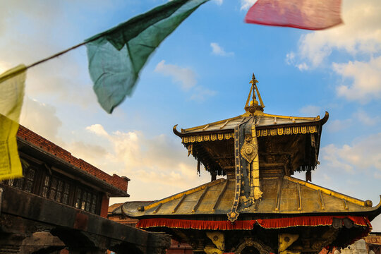 Ancient temple with prayer flags at sunset