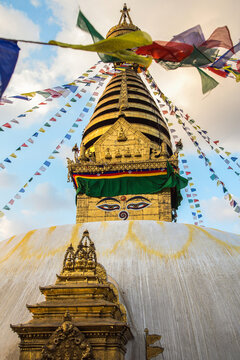 Golden Swayambhunath stupa with prayer flags at sunset