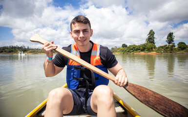young man in life jacket rowing a small boat on a lake