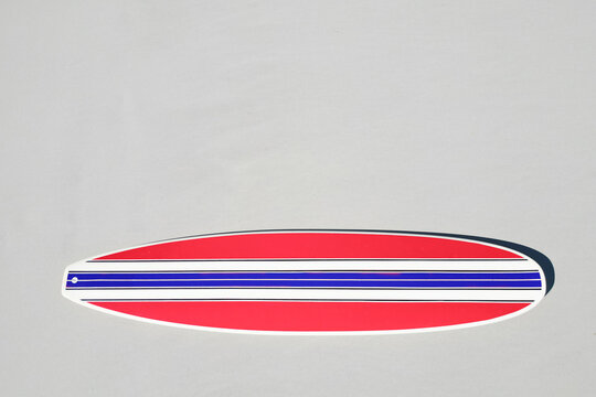 Retro red, white and blue surfboard on a beach. Sand with copy space.