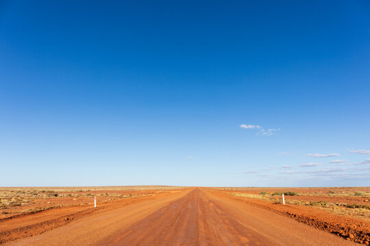 Remote red dirt road. Outback Australia. Blue sky with copy space.