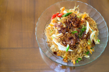 Fried rice vermicelli mixed with cabbage and carrots sprinkled with fried onions, served in a bowl. A famous spicy street food menu in Asia, oriental food, chinese food.