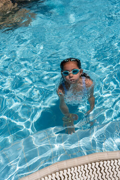 Child with goggles enjoying a swim in electric blue pool