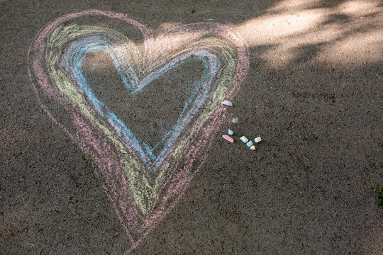 boy drawing heart with crayons outdoor 