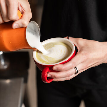 Barista pouring milk to create latte art